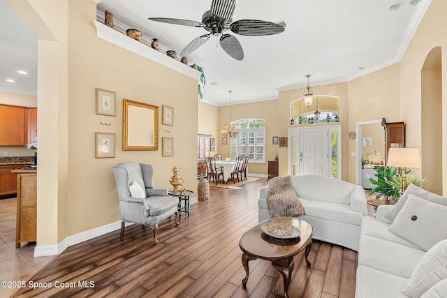 living room with ceiling fan with notable chandelier, dark hardwood / wood-style flooring, and crown molding