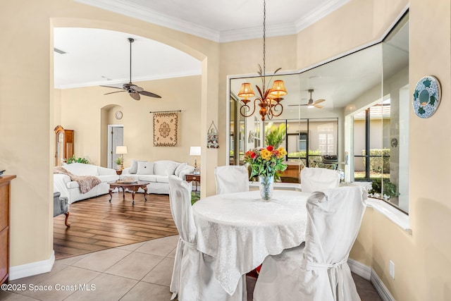 dining space featuring light tile patterned floors, ceiling fan with notable chandelier, and ornamental molding