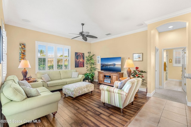 living room featuring ceiling fan, light tile patterned floors, and crown molding