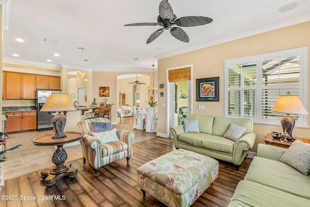 living room with crown molding, ceiling fan, and wood-type flooring