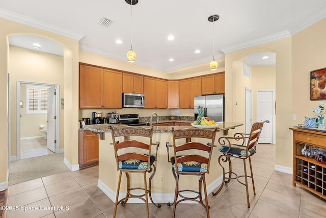 kitchen with appliances with stainless steel finishes, a center island with sink, and a kitchen breakfast bar