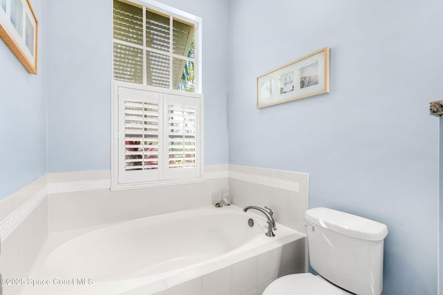 bathroom with tiled bath, toilet, and a wealth of natural light