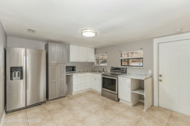 kitchen with sink, light stone counters, white cabinetry, and stainless steel appliances