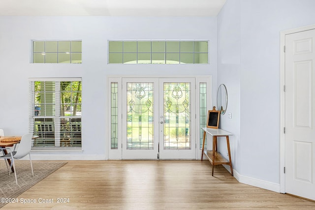 doorway to outside with a towering ceiling, a wealth of natural light, and french doors