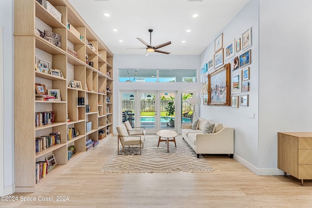 living area featuring ceiling fan, built in features, light wood-type flooring, and french doors