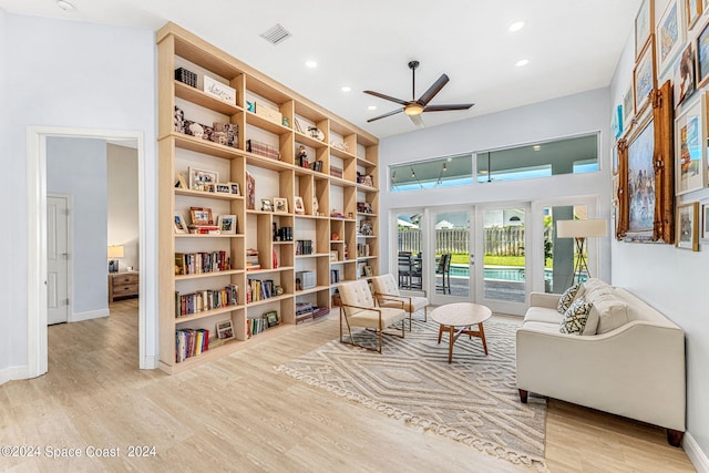 sitting room with ceiling fan, built in features, light wood-type flooring, and french doors