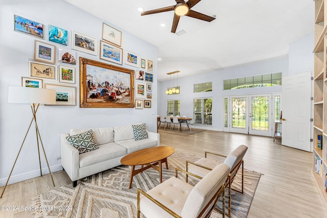 living room with french doors, light hardwood / wood-style flooring, and ceiling fan with notable chandelier