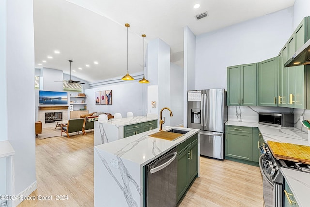 kitchen with green cabinets, light stone countertops, sink, and stainless steel appliances