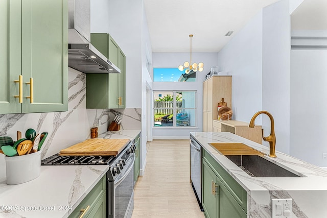 kitchen featuring appliances with stainless steel finishes, green cabinetry, and wall chimney range hood