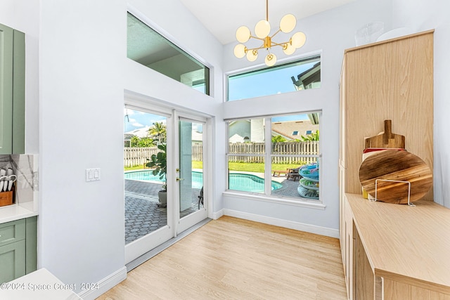 doorway to outside with light hardwood / wood-style floors and an inviting chandelier