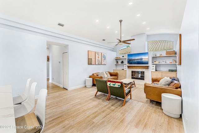 living room with ceiling fan, light hardwood / wood-style floors, built in features, and lofted ceiling