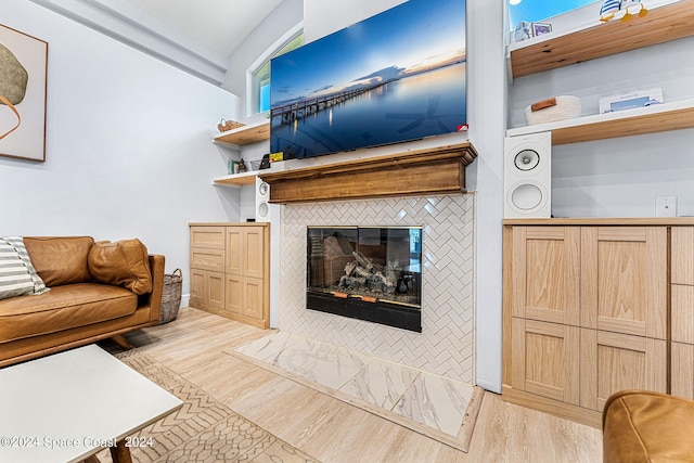 living room with a tile fireplace and light hardwood / wood-style flooring