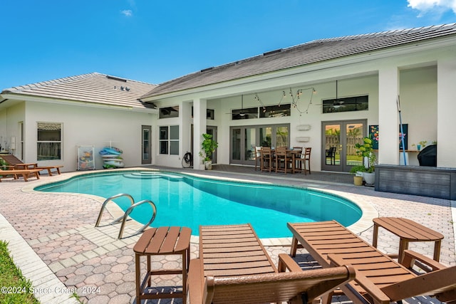 view of swimming pool with ceiling fan, a patio, and french doors