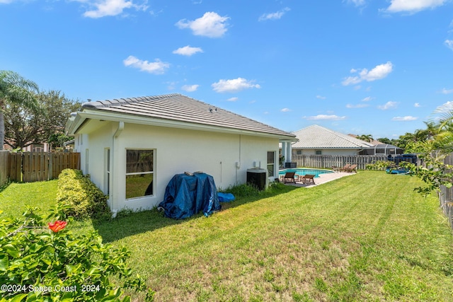 back of house featuring a yard, a fenced in pool, and cooling unit