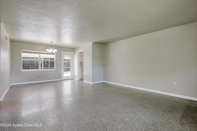 unfurnished room featuring a textured ceiling and an inviting chandelier