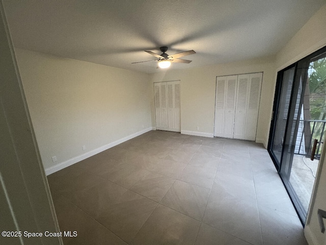 unfurnished bedroom featuring ceiling fan and multiple closets