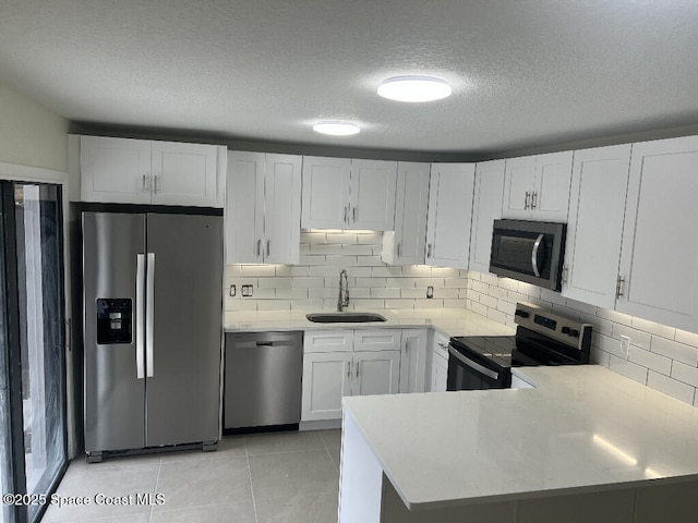 kitchen with kitchen peninsula, a textured ceiling, stainless steel appliances, white cabinets, and sink