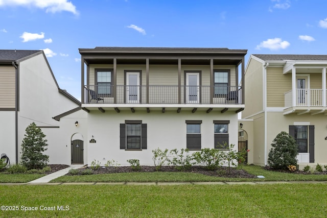 view of front of home with a balcony and a front lawn