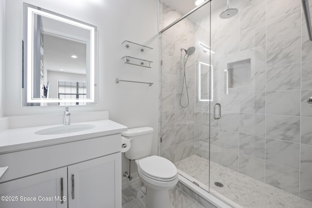 bathroom with a shower with door, vanity, and toilet