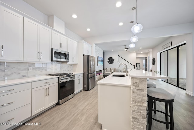 kitchen with a kitchen island with sink, sink, white cabinets, and appliances with stainless steel finishes