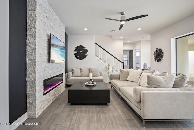 living room featuring ceiling fan and a fireplace