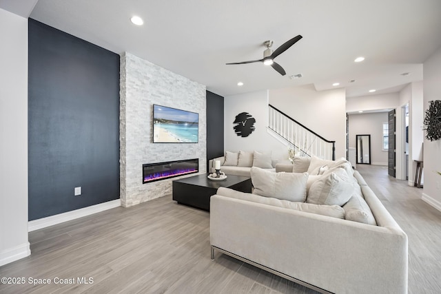 living room featuring a fireplace, wood-type flooring, and ceiling fan