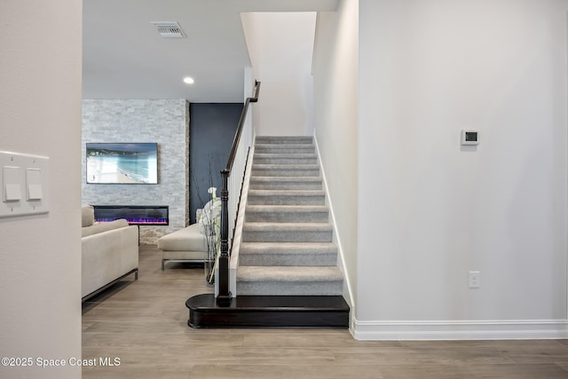 stairs featuring wood-type flooring and a fireplace