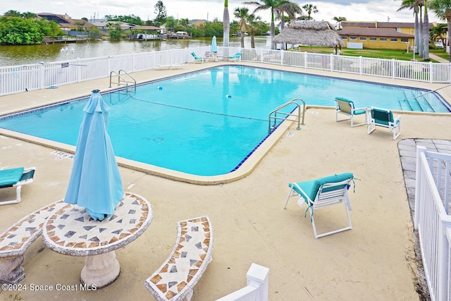 view of pool featuring a water view and a patio