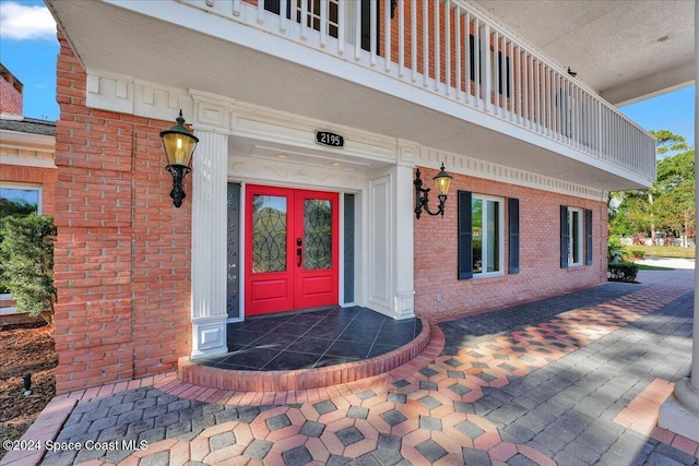 view of exterior entry featuring a balcony and french doors