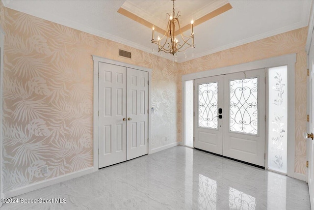 foyer with french doors, a chandelier, and ornamental molding