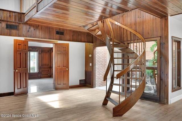 stairway with hardwood / wood-style floors, a towering ceiling, plenty of natural light, and wooden walls