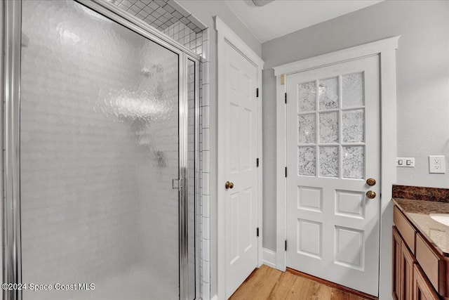 bathroom featuring a shower with door, vanity, and hardwood / wood-style flooring