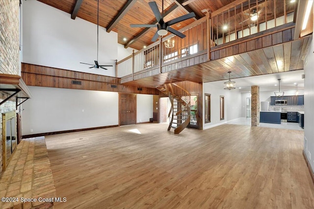 unfurnished living room with high vaulted ceiling, ceiling fan with notable chandelier, beam ceiling, wood-type flooring, and wood ceiling