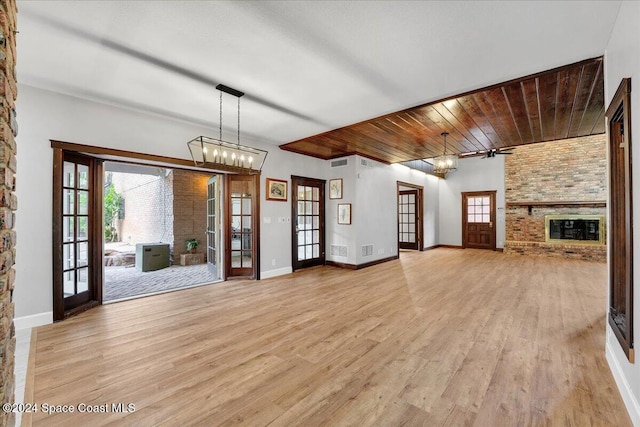 unfurnished living room featuring a fireplace, french doors, ceiling fan with notable chandelier, and wooden ceiling