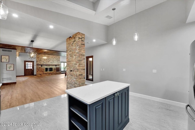 kitchen featuring blue cabinetry, ornate columns, hanging light fixtures, and a kitchen island