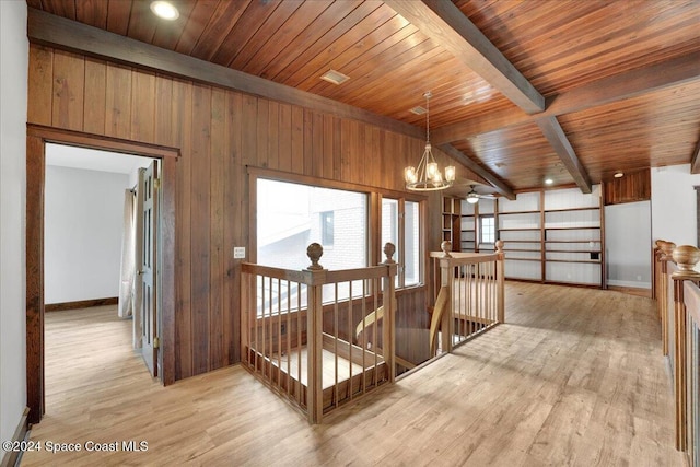 corridor with wood ceiling, a notable chandelier, beamed ceiling, light hardwood / wood-style floors, and wood walls