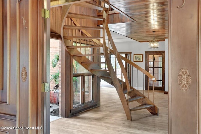 stairs featuring wooden ceiling, hardwood / wood-style flooring, and a notable chandelier