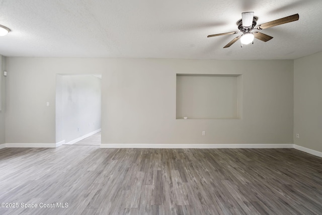 empty room featuring a textured ceiling, a ceiling fan, baseboards, and wood finished floors