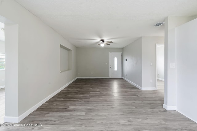 spare room with visible vents, baseboards, wood finished floors, a textured ceiling, and a ceiling fan