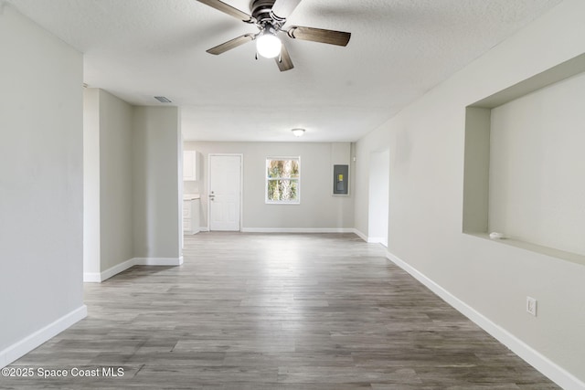 unfurnished room featuring electric panel, wood finished floors, visible vents, and baseboards