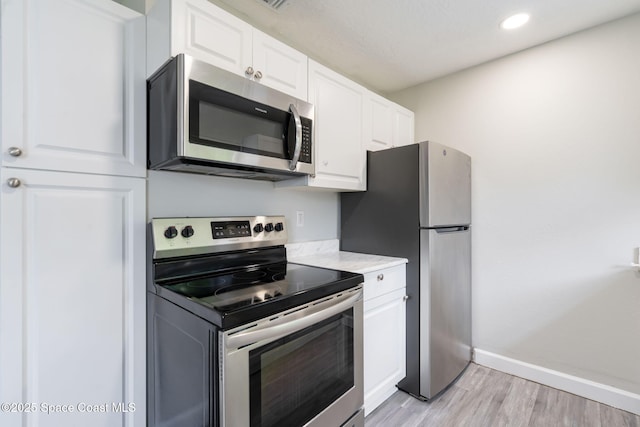 kitchen with baseboards, recessed lighting, stainless steel appliances, light wood-style floors, and white cabinetry