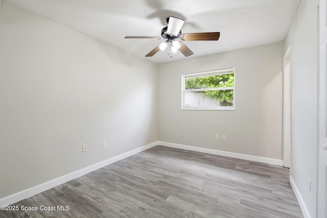 unfurnished room featuring ceiling fan, a textured ceiling, baseboards, and wood finished floors