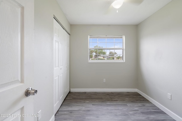 unfurnished bedroom featuring wood finished floors, baseboards, a closet, and ceiling fan