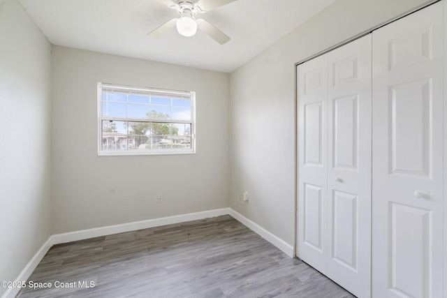 unfurnished bedroom featuring a closet, ceiling fan, baseboards, and wood finished floors