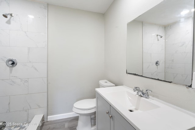 full bathroom featuring vanity, wood finished floors, baseboards, a tile shower, and toilet