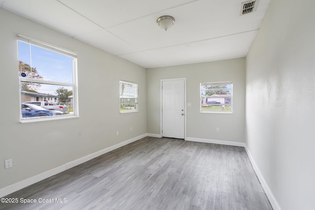 unfurnished room with visible vents, wood finished floors, and baseboards