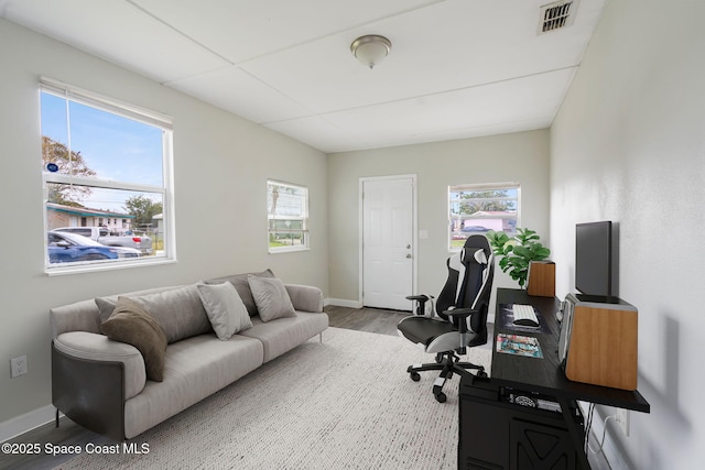 office area featuring a wealth of natural light, visible vents, baseboards, and wood finished floors