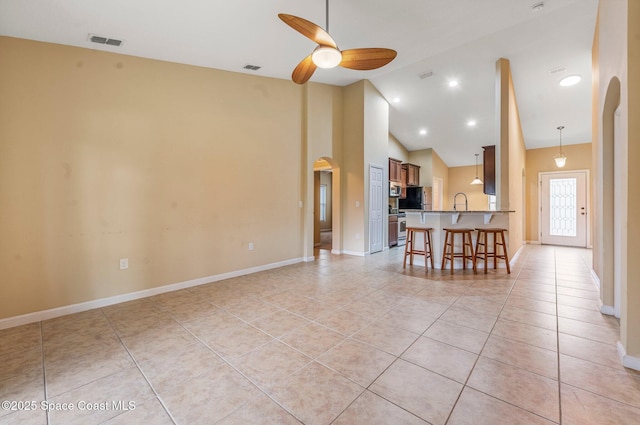 living room with ceiling fan, light tile patterned floors, sink, and high vaulted ceiling