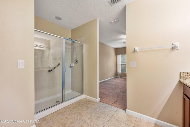 bathroom featuring tile patterned flooring, vanity, a shower with shower door, and a textured ceiling