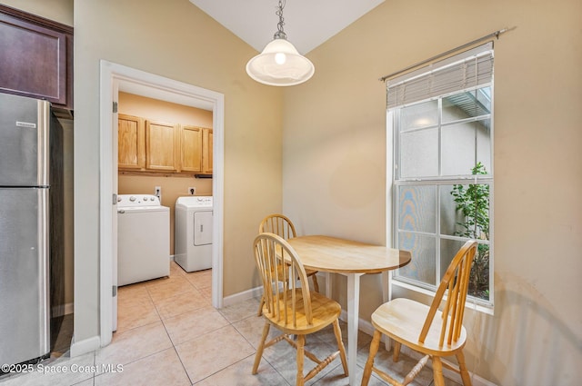 dining area featuring lofted ceiling, washing machine and dryer, and light tile patterned floors